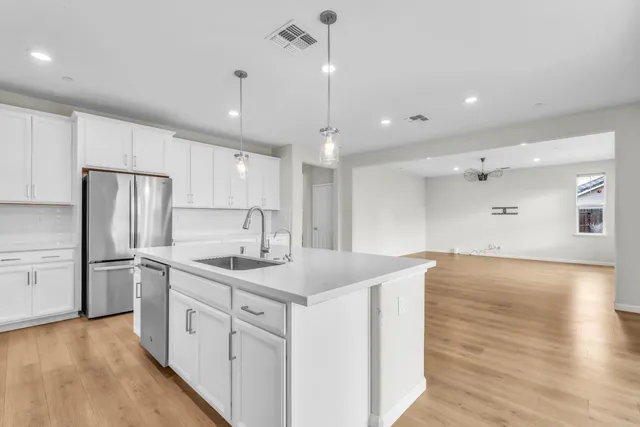 a kitchen with stainless steel appliances granite countertop a sink a oven a dining table and chairs with wooden floor