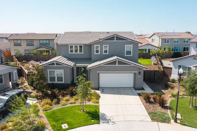 a front view of a house with a yard and potted plants