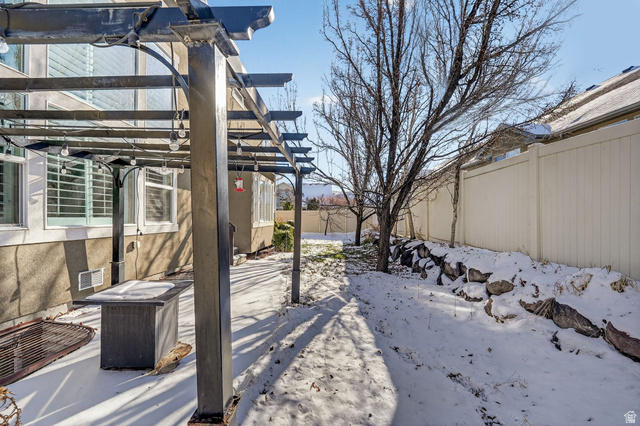 14714 South Bright Wood Road Herriman, UT 84096 - Photo 39 of 41 Fenced back yard layered in snow with a pergola and firepit