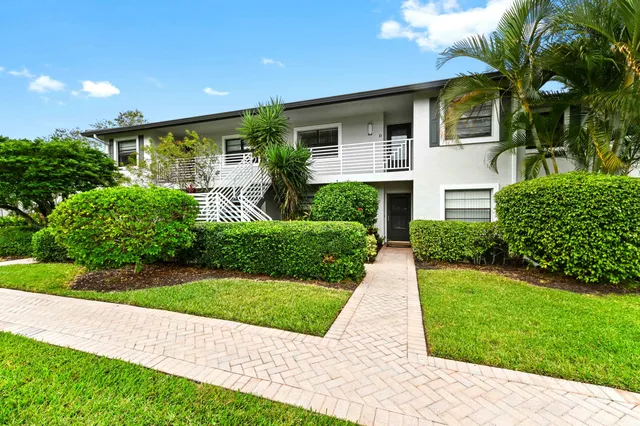 a front view of a house with a yard and potted plants