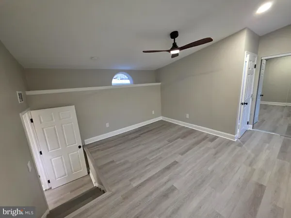 an empty room with wooden floor fan and windows