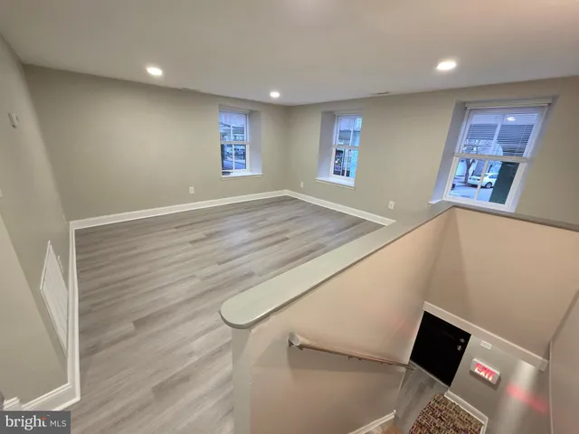a view of an empty room with windows and wooden floor