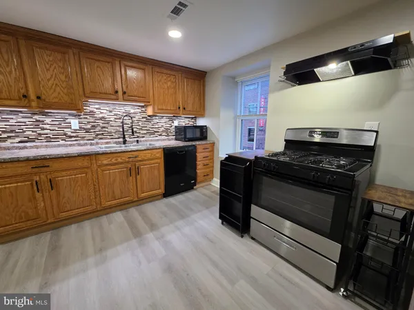a kitchen with granite countertop wooden cabinets and a stove top oven