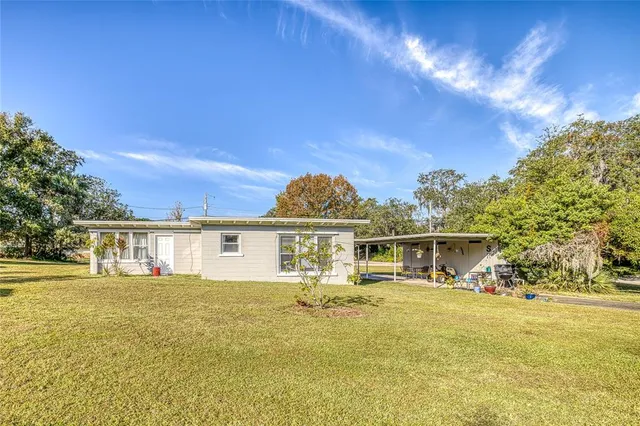 a view of a house with a big yard and large trees