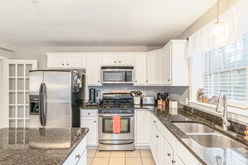 1975 Middlesex Street, Unit 2 Lowell, MA 01851 - Photo 7 of 31 a kitchen with stainless steel appliances granite countertop a sink a stove a refrigerator a counter space and cabinets