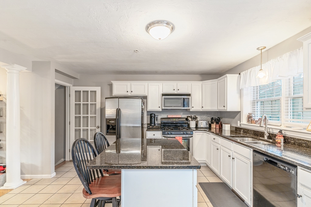 1975 Middlesex Street, Unit 2 Lowell, MA 01851 - Photo 8 of 31 a kitchen with stainless steel appliances granite countertop a stove top oven a sink dishwasher a dining table and chairs with wooden floor