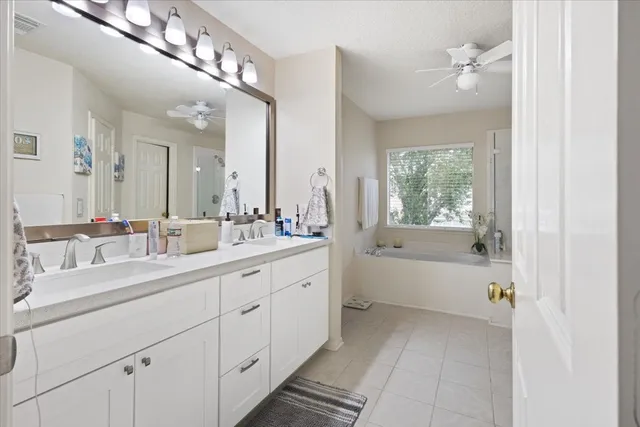 a spacious en suite bathroom with a double vanity sink a large mirror and a bathtub