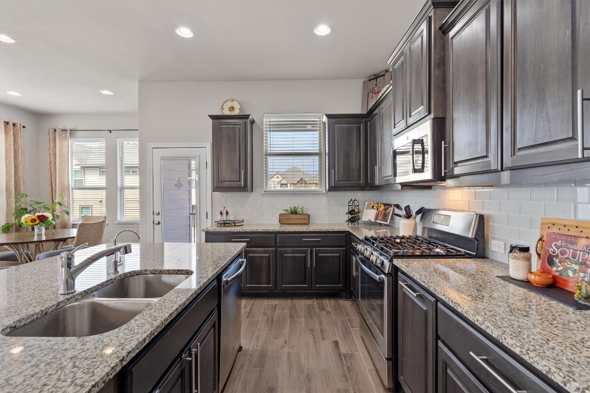 a kitchen with granite countertop a sink a counter space appliances and cabinets
