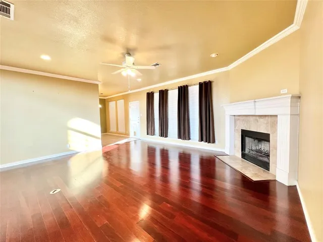 a view of an empty room with wooden floor and a fireplace