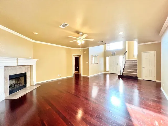 a view of an empty room with wooden floor and a fireplace