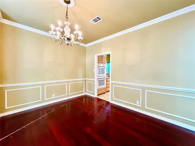 a view of an empty room with kitchen and wooden floor