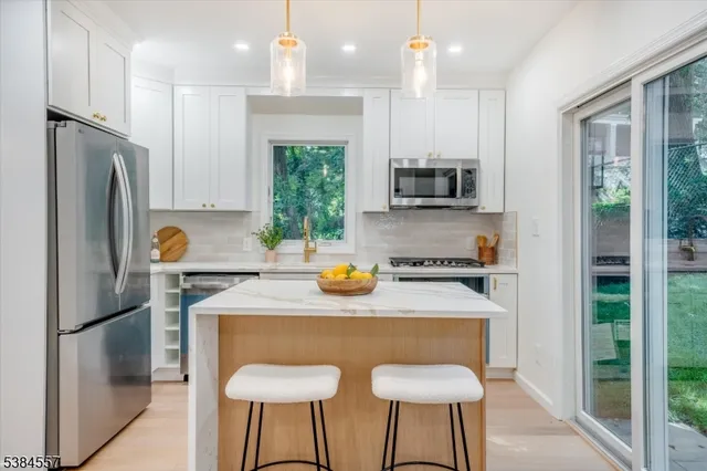 a kitchen with stainless steel appliances granite countertop a refrigerator a sink a stove and a refrigerator