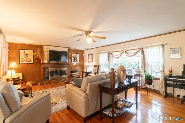 a living room with furniture a ceiling fan a fireplace and a large window