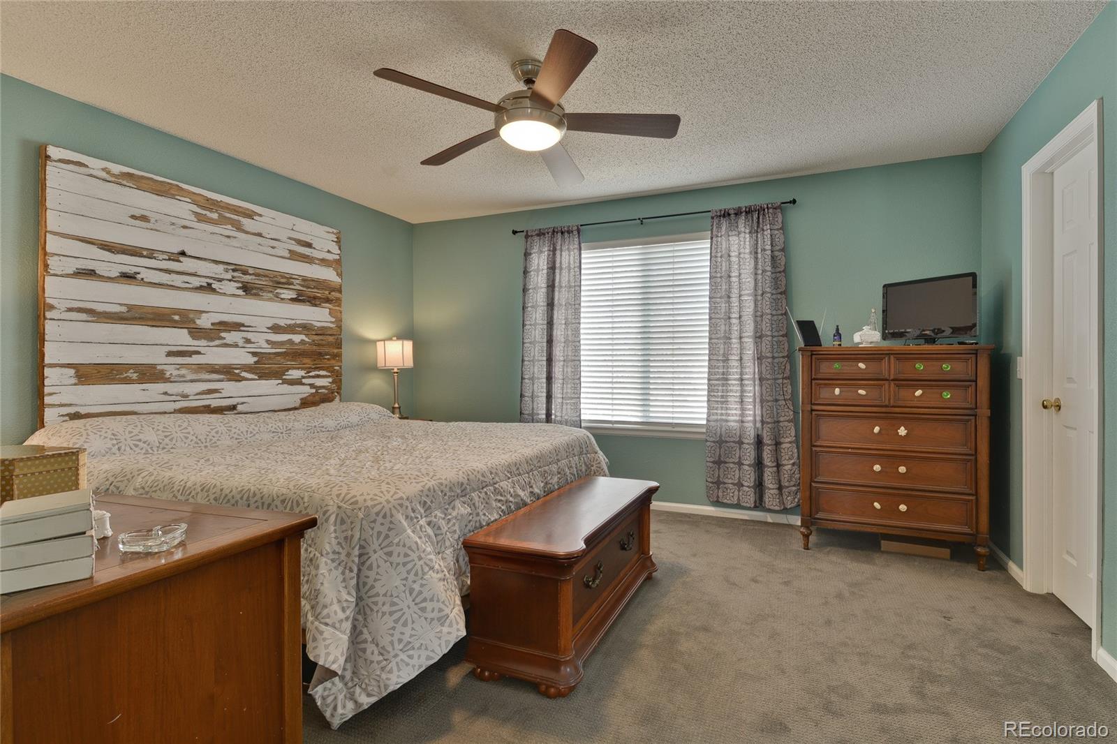 1165 Timbervale Trail Highlands Ranch, CO 80129 - Photo 16 of 29 a bedroom with a bed and a chandelier