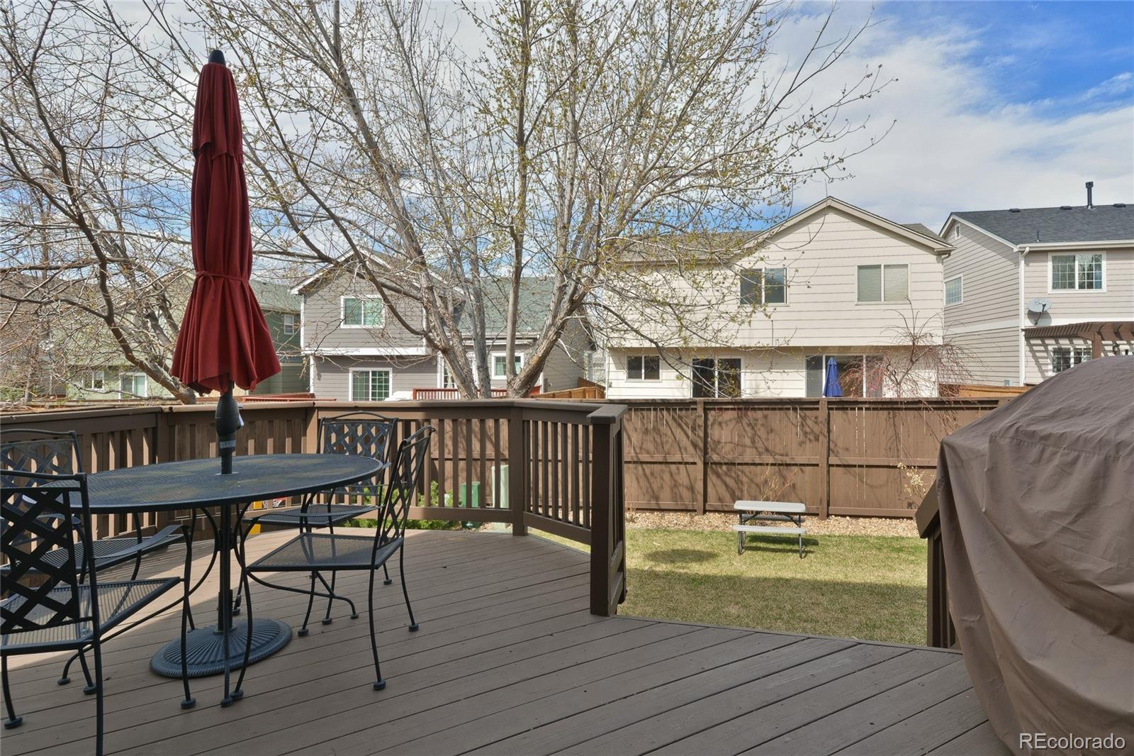 1165 Timbervale Trail Highlands Ranch, CO 80129 - Photo 25 of 29 a view of a house with wooden deck and a table