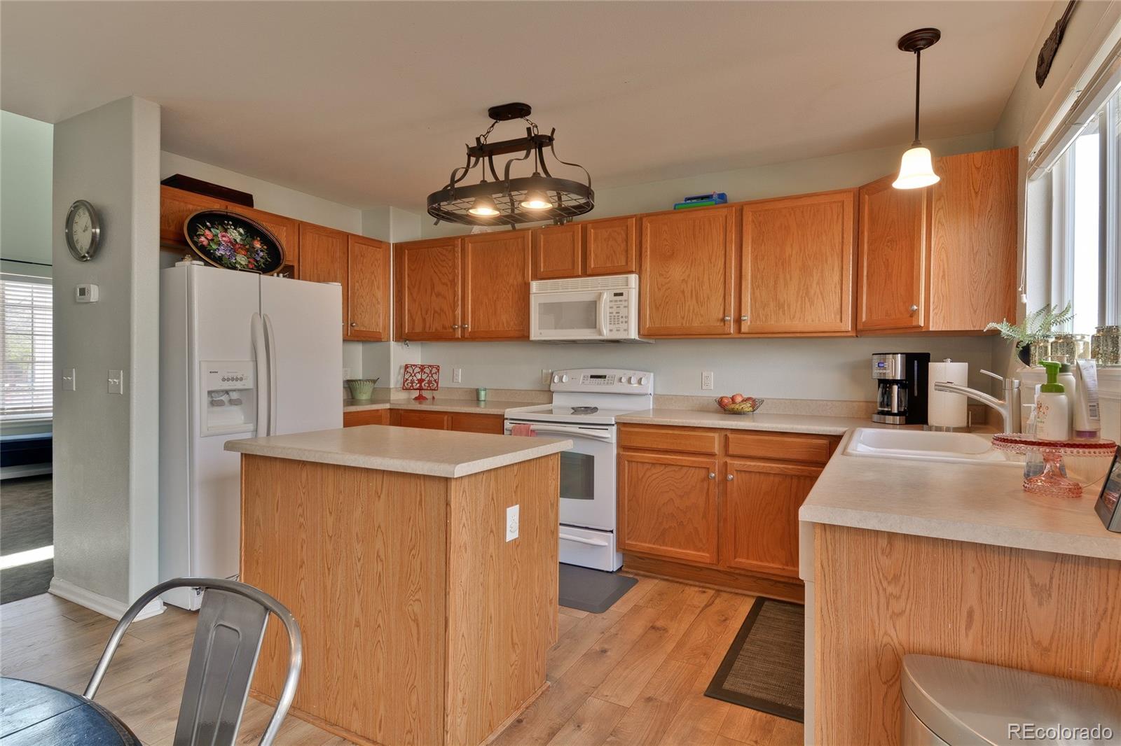 1165 Timbervale Trail Highlands Ranch, CO 80129 - Photo 7 of 29 a kitchen with stainless steel appliances granite countertop a refrigerator a sink dishwasher a stove and white cabinets with wooden floor
