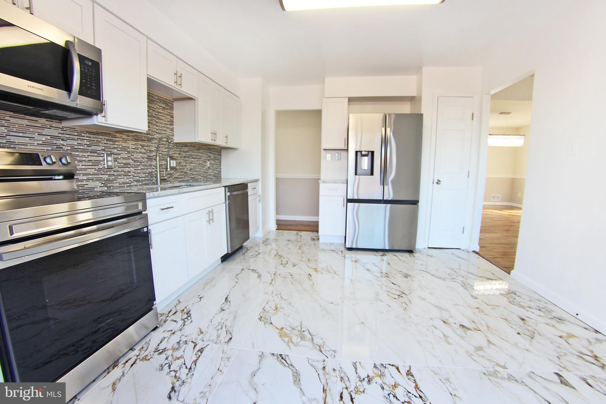 8916 Goldfield Place Clinton, MD 20735 - Photo 7 of 24 a kitchen with granite countertop a refrigerator and a stove top oven