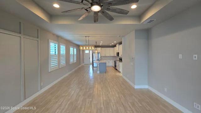 a view of a room with wooden floor fan and windows