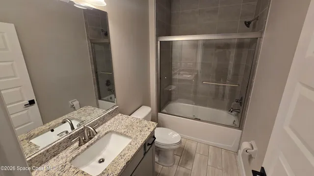 a bathroom with a granite countertop sink a toilet and shower