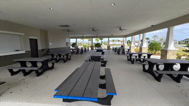 a room with lots of tables a large window and furniture