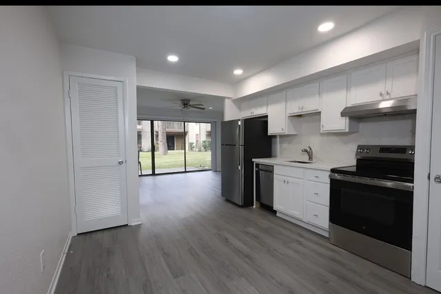 a kitchen with a refrigerator a stove top oven and wooden floor