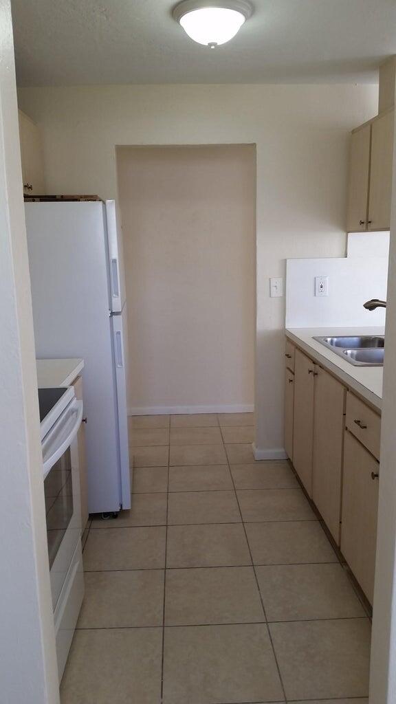 1230 West 23rd Street Riviera Beach, FL 33404 - Photo 4 of 19 a kitchen with a sink a stove top oven and cabinets
