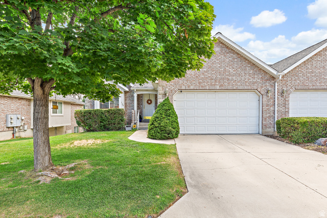 148 South Ridgeview Drive Orem, UT 84058 - Photo 2 of 23 Brick exterior featuring a two-car garage with white panel doors, concrete driveway, front lawn, and mature tree