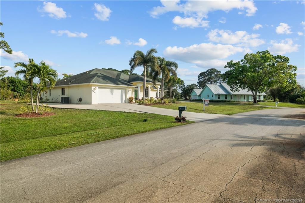 2457 Southeast Issac Road Port St. Lucie, FL 34952 - Photo 5 of 51 a view of a house with a big yard and palm trees