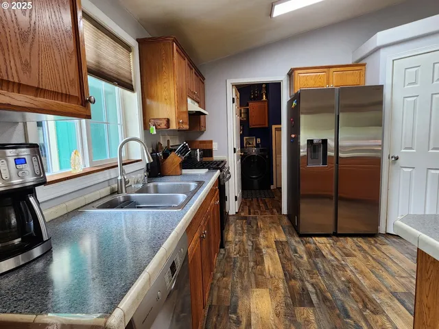 a kitchen with stainless steel appliances granite countertop a sink a stove and a refrigerator