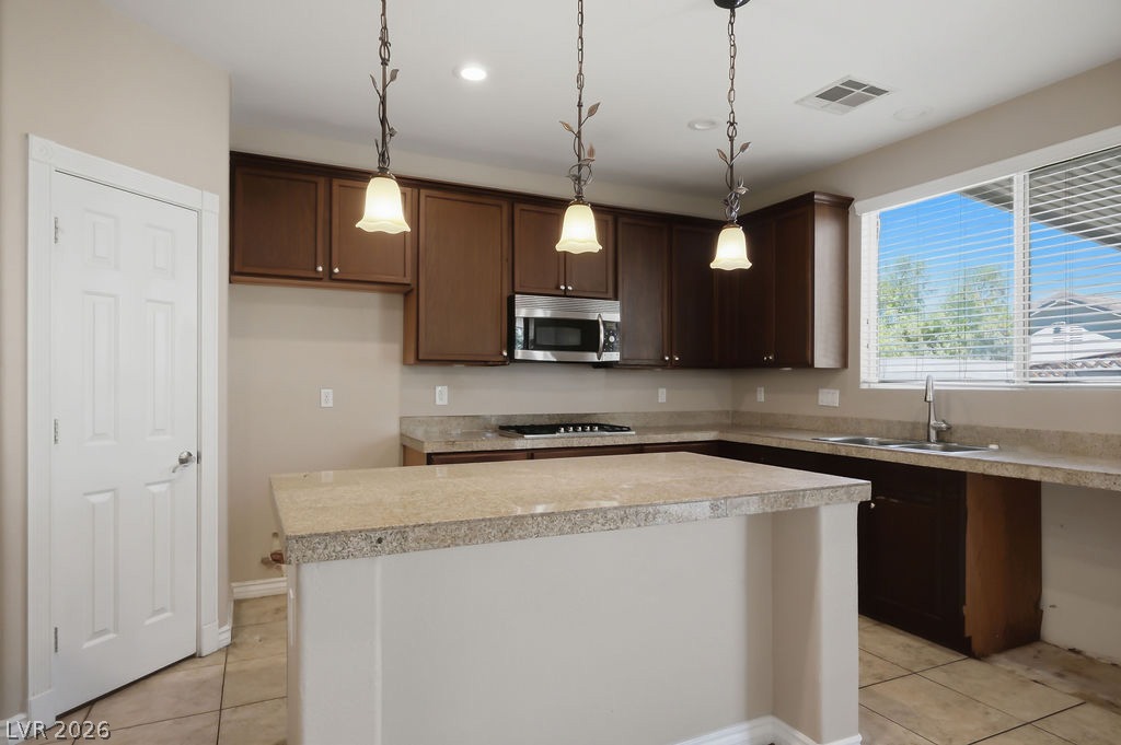 9712 North Running Rabbit Street Las Vegas, NV 89143 - Photo 16 of 42 A well-lit kitchen with rich cabinetry and ample counter space, featuring a functional island.