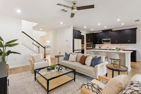 a living room with furniture kitchen view and a wooden floor