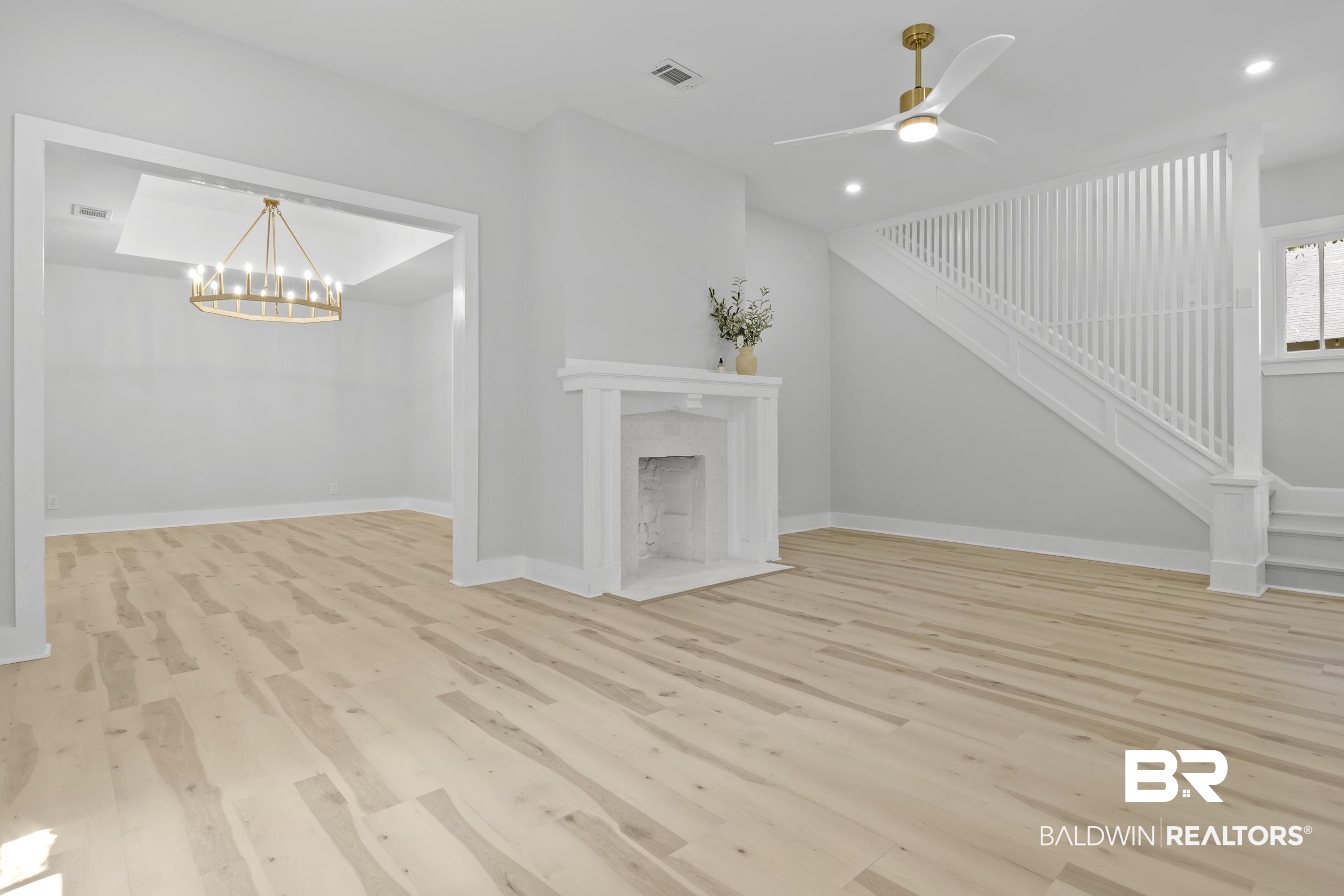 315 Park Avenue Mobile, AL 36607 - Photo 10 of 27 Unfurnished living room with ceiling fan with notable chandelier, a high end fireplace, and light hardwood / wood-style floors