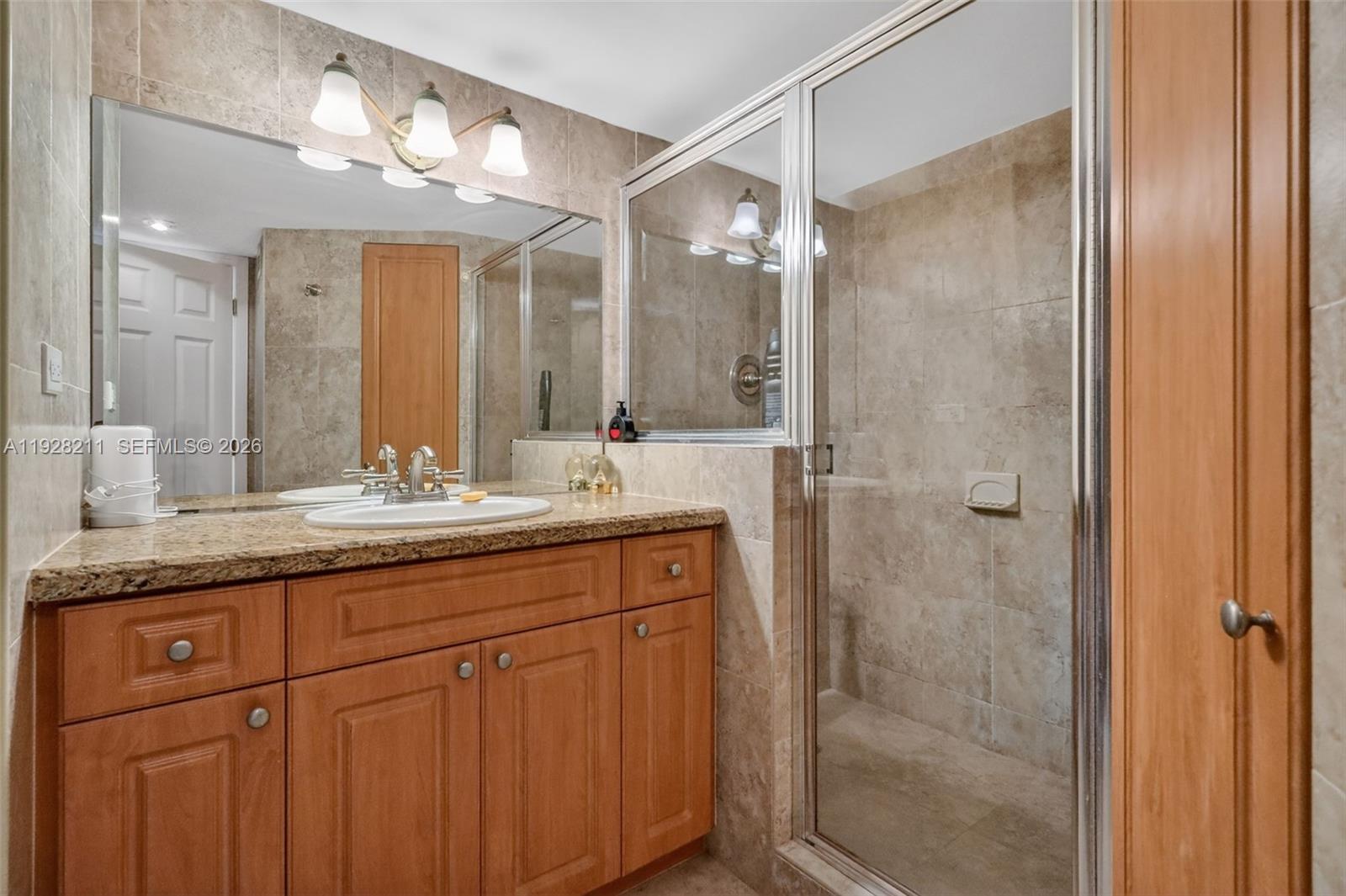 7135 Collins Avenue, Unit 1015 Miami Beach, FL 33141 - Photo 16 of 41 a bathroom with a granite countertop sink a mirror and a shower