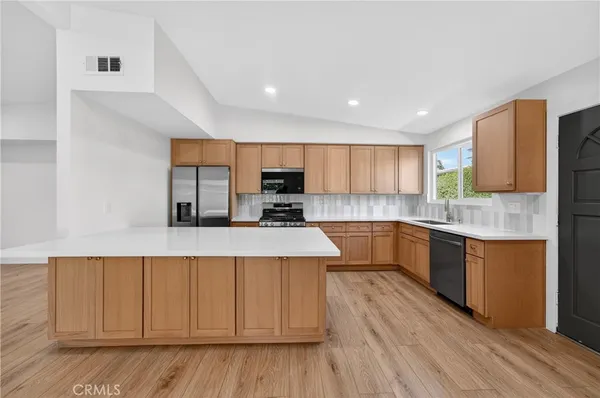 a large kitchen with a center island and stainless steel appliances