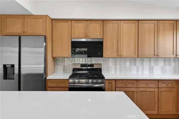 a kitchen with granite countertop a stove a sink and a refrigerator