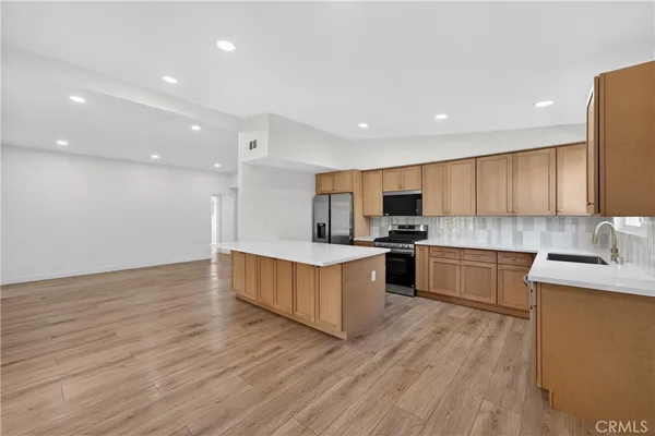 a large kitchen with stainless steel appliances granite countertop a large counter top a stove and a wooden floors