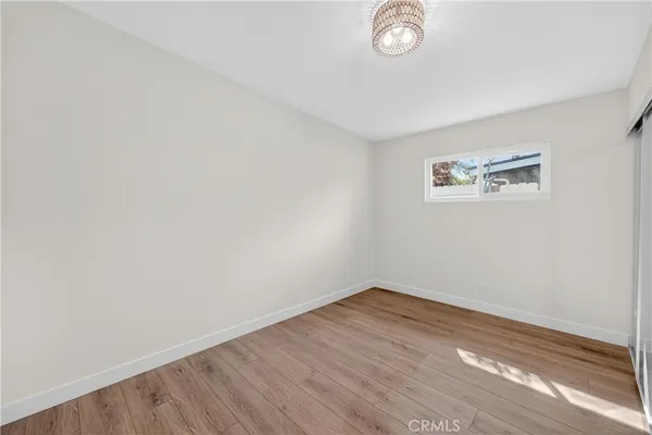 a view of empty room with wooden floor and window