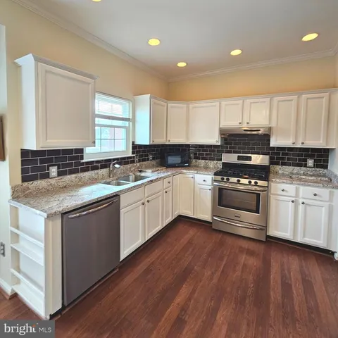 a kitchen with stainless steel appliances granite countertop a sink cabinets and wooden floors