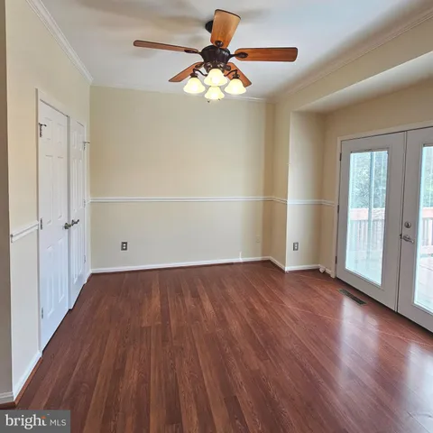 an empty room with wooden floor chandelier fan and windows