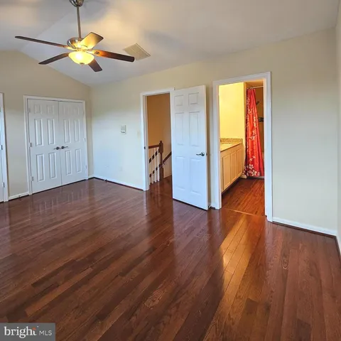 an empty room with wooden floor and a chandelier fan