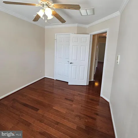 an empty room with wooden floor and ceiling fan