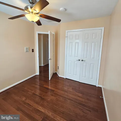 a view of an empty room with window a ceiling fan and wooden floor
