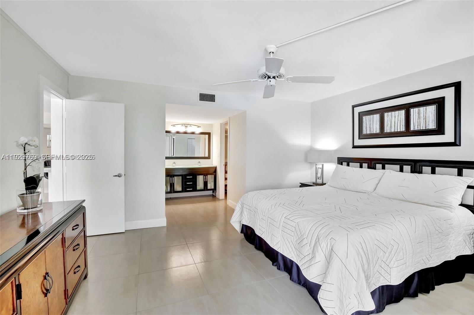 3930 Inverrary Boulevard, Unit 405D Lauderhill, FL 33319 - Photo 22 of 46 a spacious bedroom with a bed and a chandelier