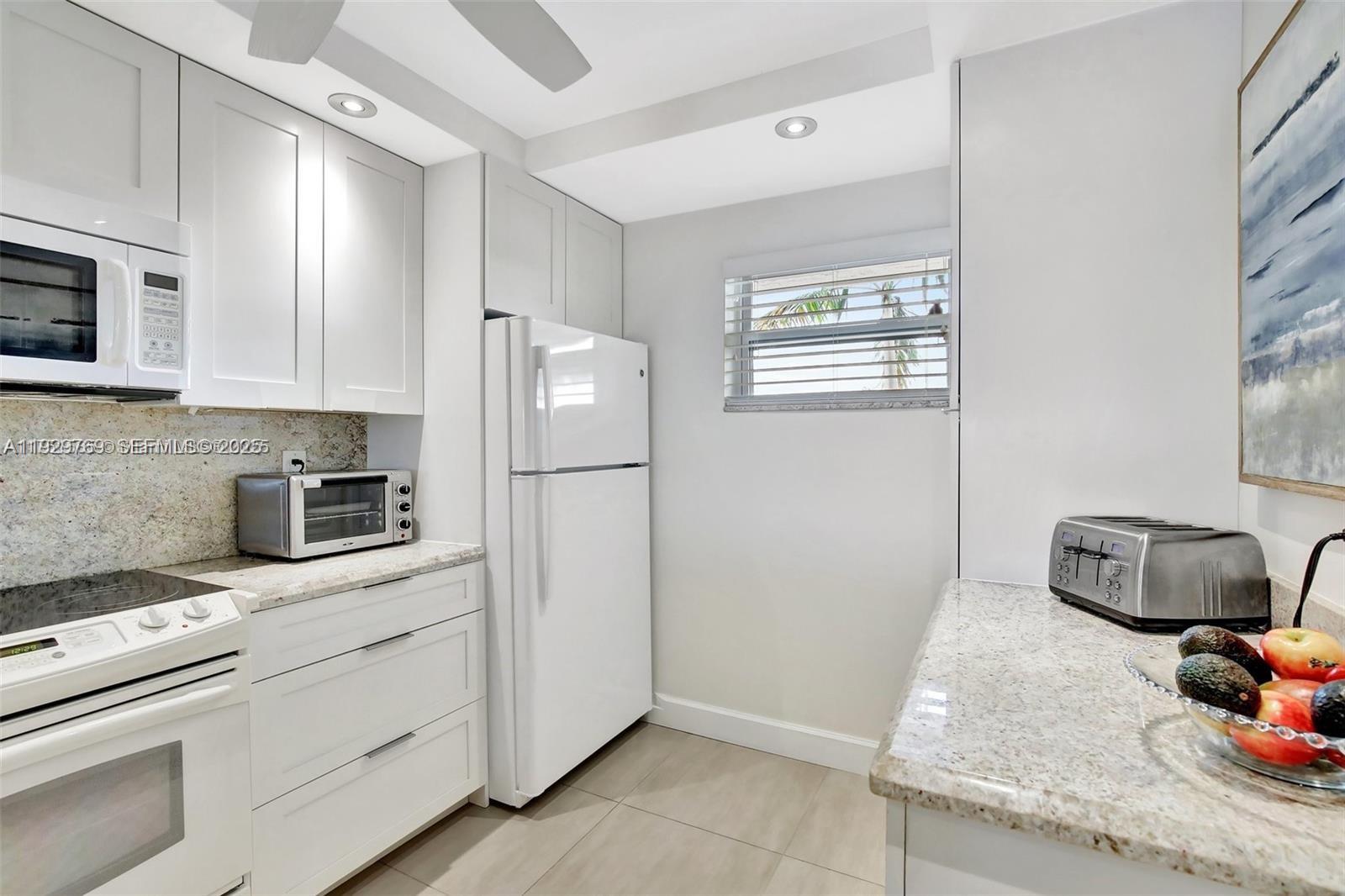 3930 Inverrary Boulevard, Unit 405D Lauderhill, FL 33319 - Photo 5 of 46 a kitchen with stainless steel appliances granite countertop a refrigerator sink and stove