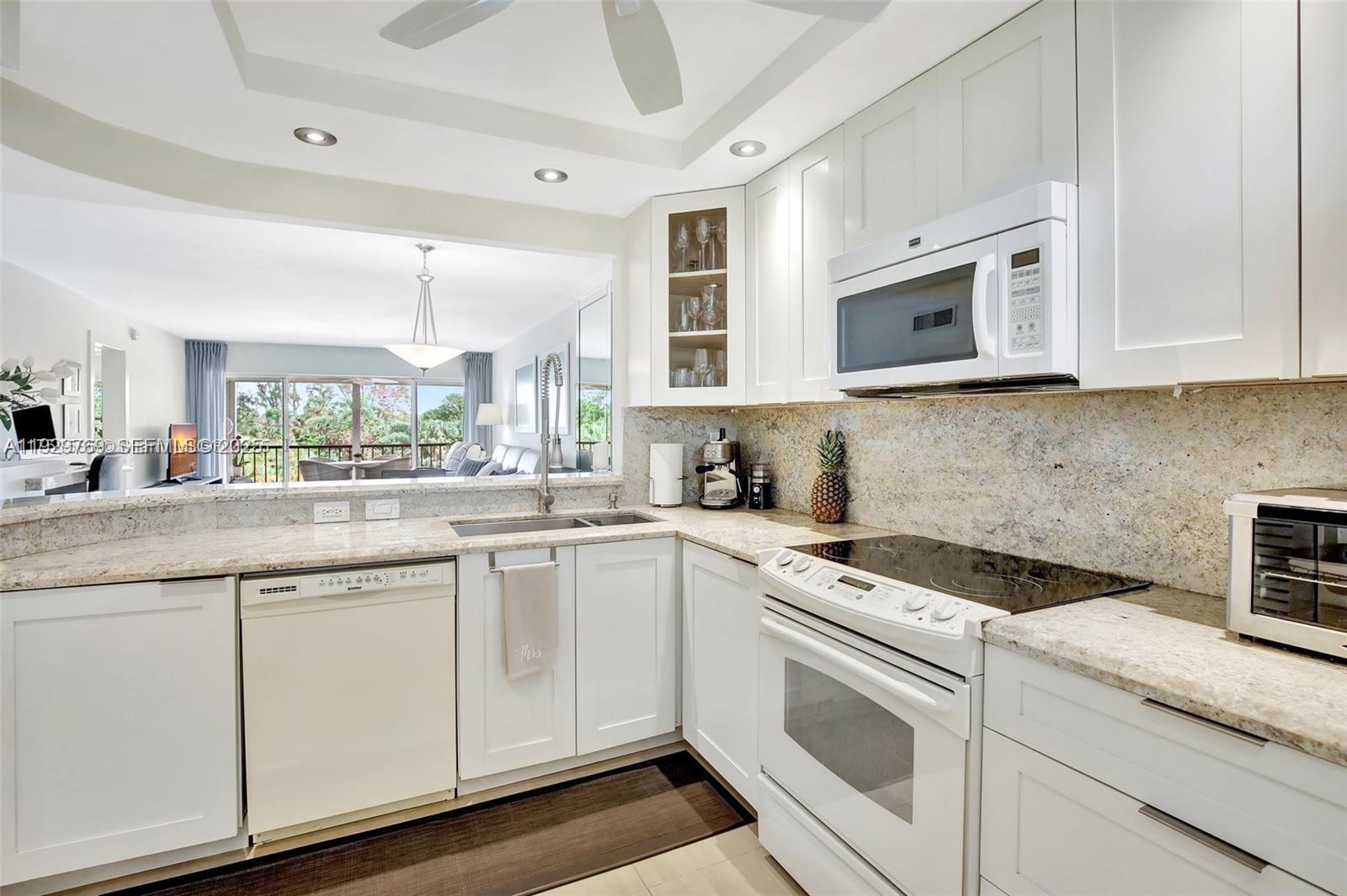 3930 Inverrary Boulevard, Unit 405D Lauderhill, FL 33319 - Photo 8 of 46 a kitchen with granite countertop white cabinets white appliances and a sink