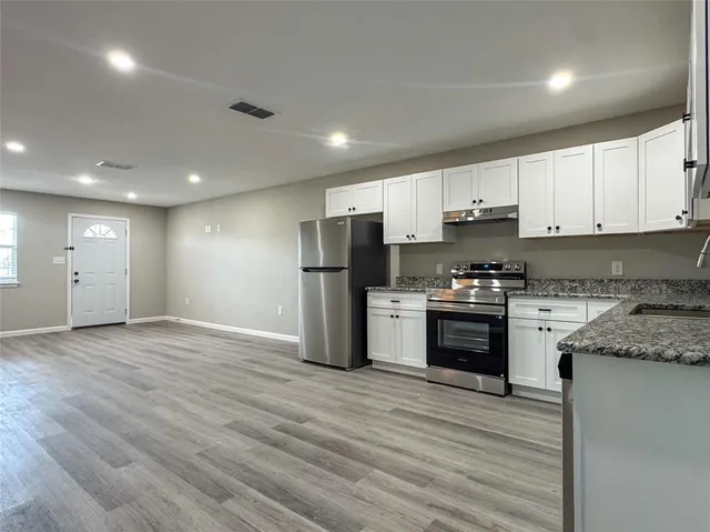 a kitchen with stainless steel appliances granite countertop a refrigerator and a stove top oven