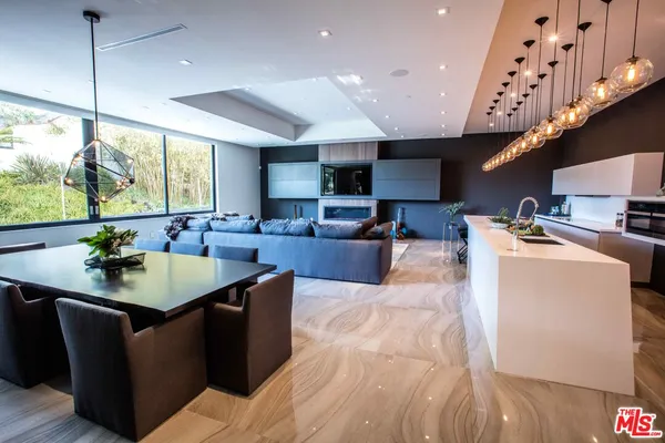 a large kitchen with stainless steel appliances granite countertop a sink a counter space and a view of living room