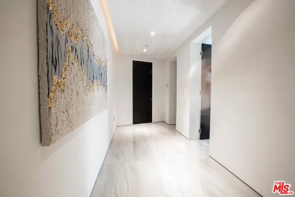 a view of a hallway with wooden floor and a bathroom