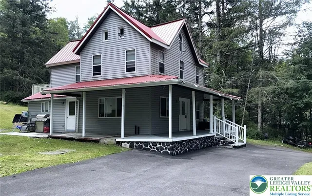 a view of a house with a yard and large tree