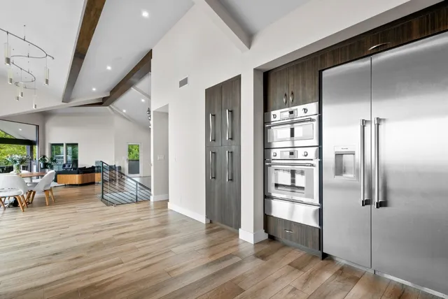 a bed sitting in a spacious bedroom next to a large window and a potted plant